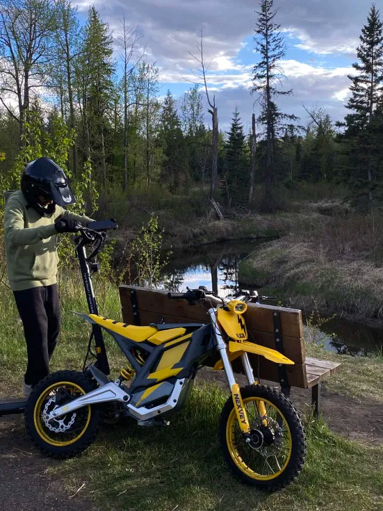 Yellow NEXVEY Flash electric dirt bike on a riverside trail