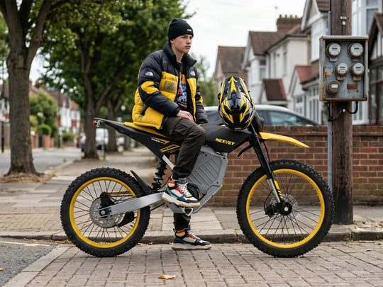 A young rider wearing a beanie and yellow jacket sitting on a yellow and black NEXVEY STORM Electric Dirt Bike beside a residential sidewalk, with a helmet on the handlebars.