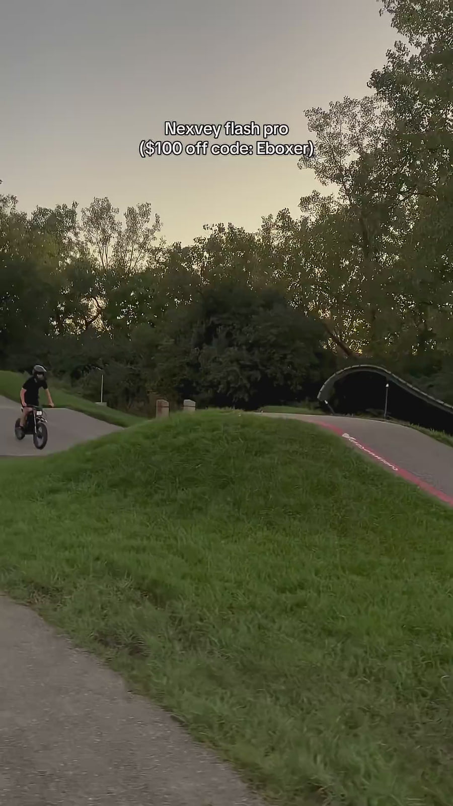 Eboxer riding a NEXVEY FLASH PRO electric dirt bike over a dirt jump at an outdoor bike track.