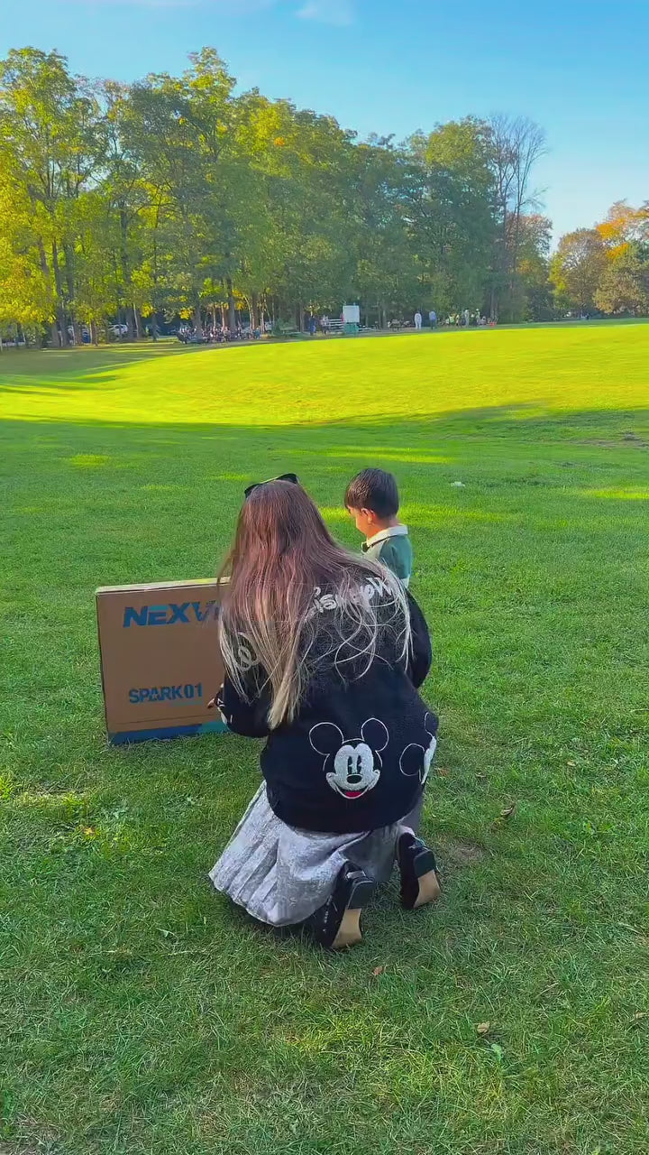 A family unboxing a blue NEXVEY electric dirt bike for a child outdoors.
