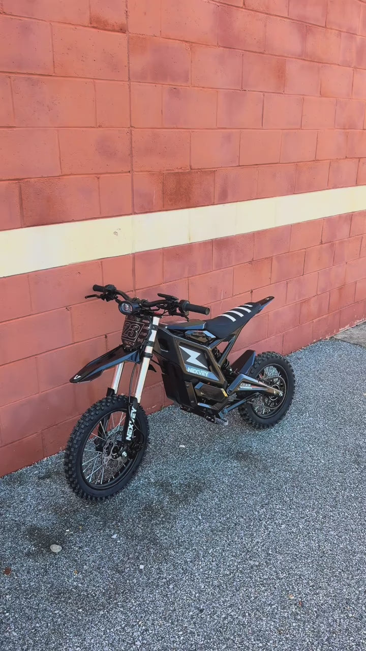 A close-up walkthrough video of the Nexvey Flash youth electric motorcycle parked on a US street, showcasing its design, Z logo, and off-road tires.