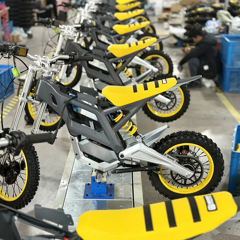 NEXVEY electric flash bikes in assembly line production, featuring sleek matte grey frames with vibrant yellow seats and off-road knobby tires in a manufacturing facility