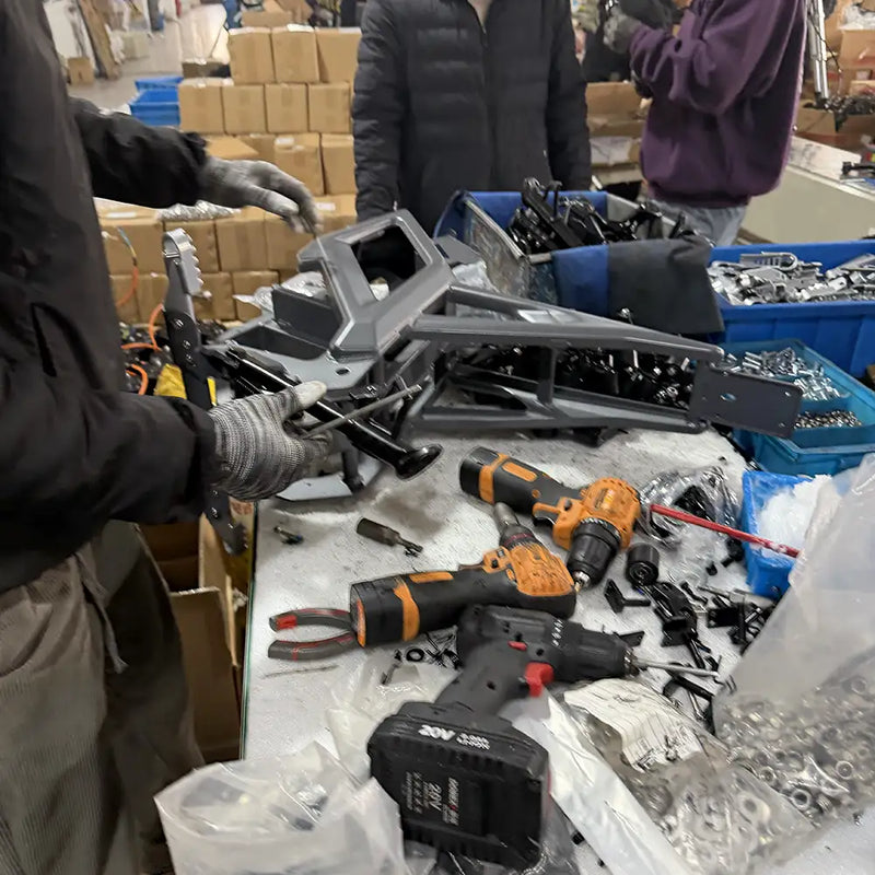 Close-up of the manual assembly process for a NEXVEY electric dirt bike, featuring professional power tools and high-grade metal chassis components