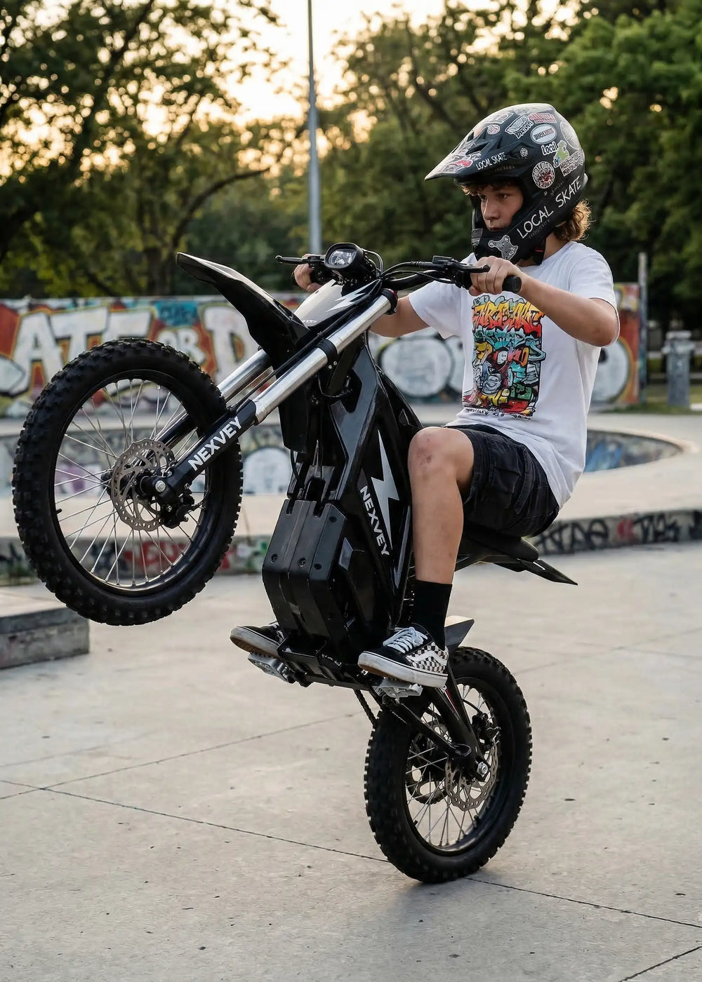 Close-up of a young rider performing a wheelie on a black NEXVEY electric dirt bike, highlighting its powerful suspension and sleek design