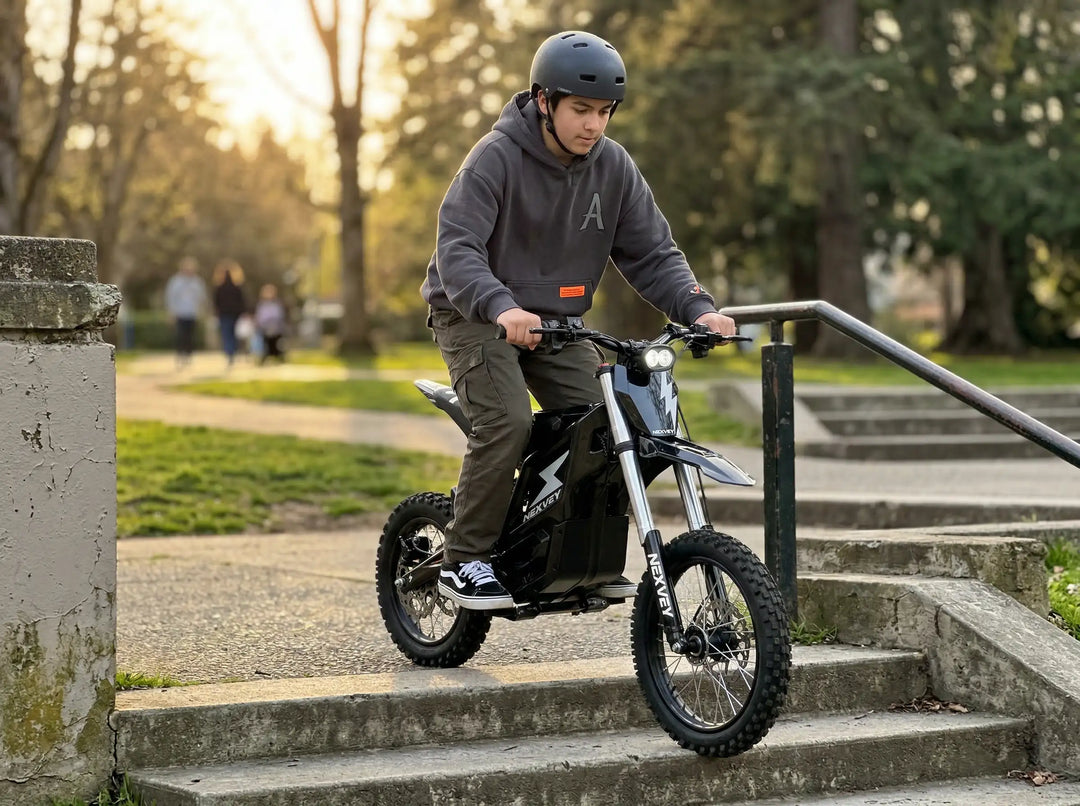 A teenager on a black NEXVEY FLASH electric dirt bike carefully navigating a descent down concrete park stairs, illuminated by a warm sunset glow