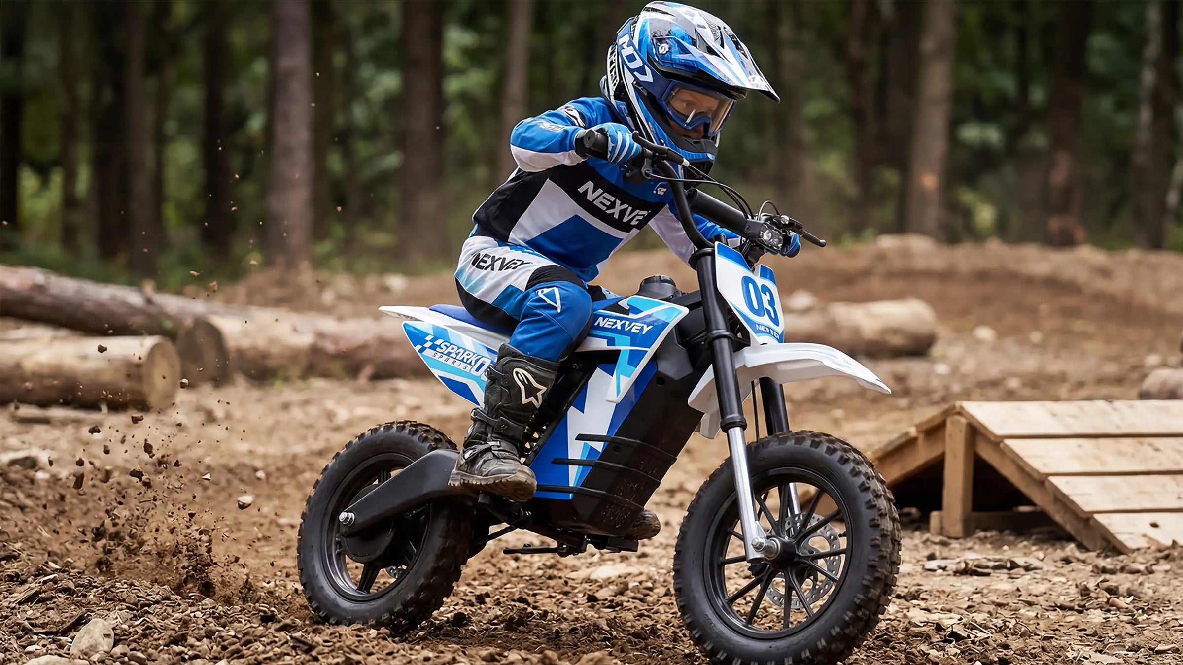 A young rider in professional racing gear and blue helmet riding a NEXVEY electric dirt bike on an off-road forest trail